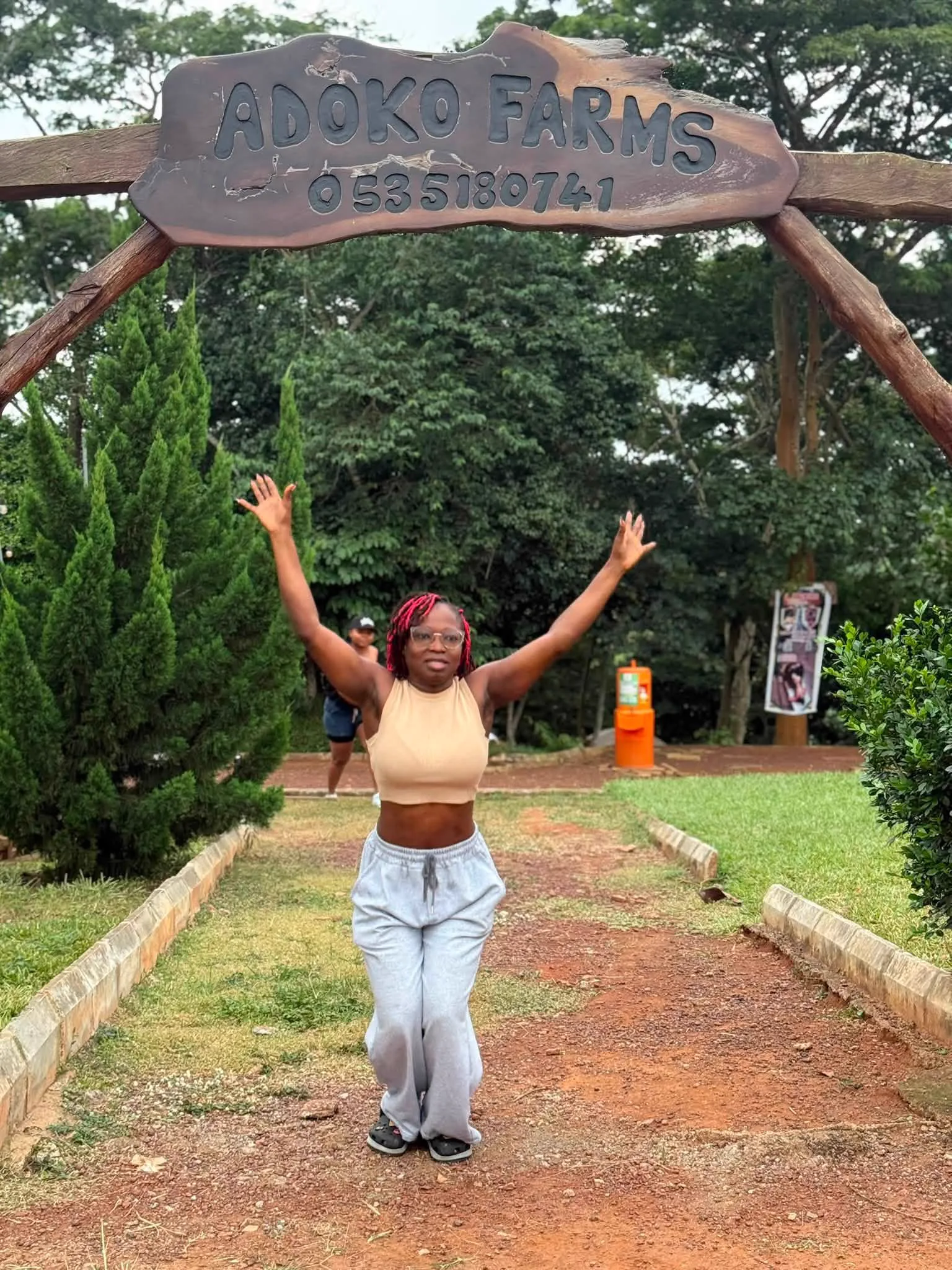The Adoko Farms entrance sign and a visitor on the path